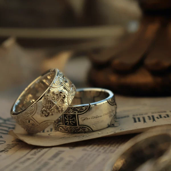 Introducing the exquisite Silveringdom collection, featuring a pair of matching rings that epitomize elegance and craftsmanship. Each ring showcases a beautifully detailed cross design, symbolizing unity and faith. The intricate patterns are highlighted by the contrasting hues of light silver and dark silver, creating a striking visual appeal. The light silver elements gleam brilliantly against the dark silver background, enhancing the depth and texture of the design. These rings are not only a testament to fine jewelry artistry but also serve as a meaningful symbol of connection. Perfect for couples, these matching rings from Silveringdom are a timeless addition to any jewelry collection, capturing both beauty and sentiment.