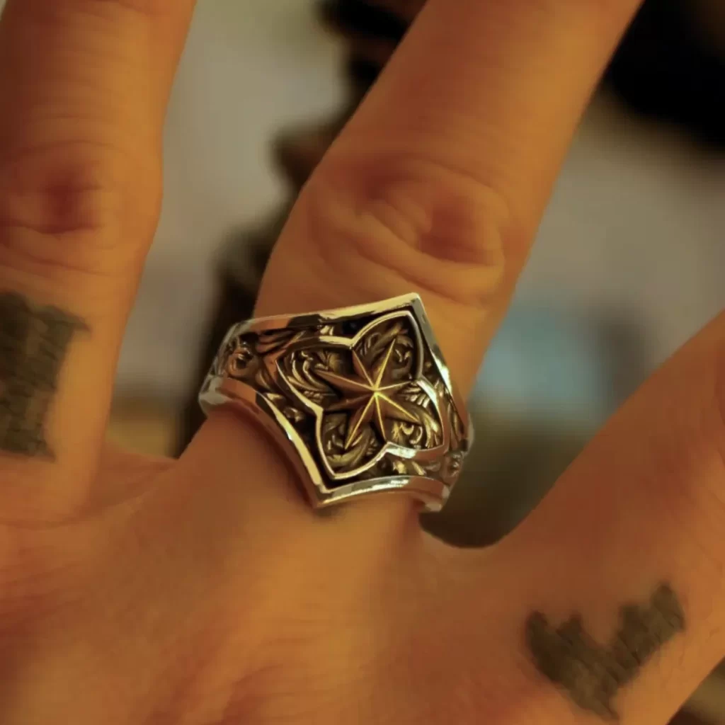 In the heart of the silveringdom, a hand adorned with dark silver rings emerges, each piece telling its own sacred tale. The most prominent ring, nestled on the ring finger, features an intricate design that evokes the celestial Polaris, guiding like a holy symbol through life’s journey. Its companions are matching rings that echo its mystical allure. The image captures these metallic treasures in a soft glow, highlighting their detailed craftsmanship and the unique story they embody. This tableau is not only a showcase of personal style but also an intimate glimpse into symbolic adornments that carry deeper meanings and connections to the cosmos.