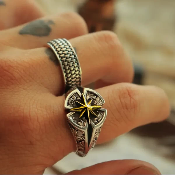 Introducing the exquisite Silveringdom Matching Rings collection, where elegance meets timeless design. These rings, crafted from dark silver, embody a sophisticated charm. The first ring features an intricate pattern with a central golden emblem shaped like Polaris, symbolizing guidance and constancy. Its companion ring, designed with tightly woven metal strands, complements the first, creating a harmonious pair. The artistry of these rings is reminiscent of the delicate layers of a rose, showcasing meticulous craftsmanship. Perfect for those who appreciate unique and meaningful jewelry, these matching rings are a testament to the beauty of Silveringdom’s creations. Ideal for couples or close friends, they symbolize unity and shared journeys.