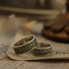 In the heart of Silveringdom’s artisan workshop, a pair of dark silver wedding rings gleams with timeless elegance. These rings, part of the Vintage Vow collection, are a testament to the art of handcraft. Each ring is meticulously crafted, showcasing intricate patterns that reflect the dedication and skill of our artisans. The dark silver hue adds a touch of sophistication, making these rings a perfect choice for those seeking a gender-neutral design. At Silveringdom, we understand that every love story is unique, which is why we offer the option to customize these wedding rings to match your personal style and story. Whether you’re celebrating a wedding, an anniversary, or a special bond, these rings symbolize a commitment that transcends time. Embrace the beauty of handcrafted jewelry with Silveringdom, where every piece is made with love and precision.